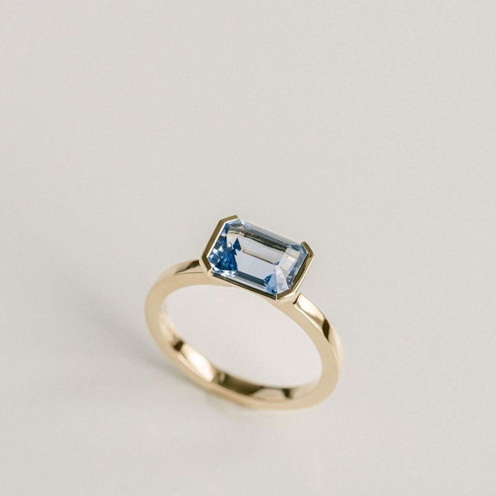 Emerald Cut Blue Sapphire East-West Half Bezel