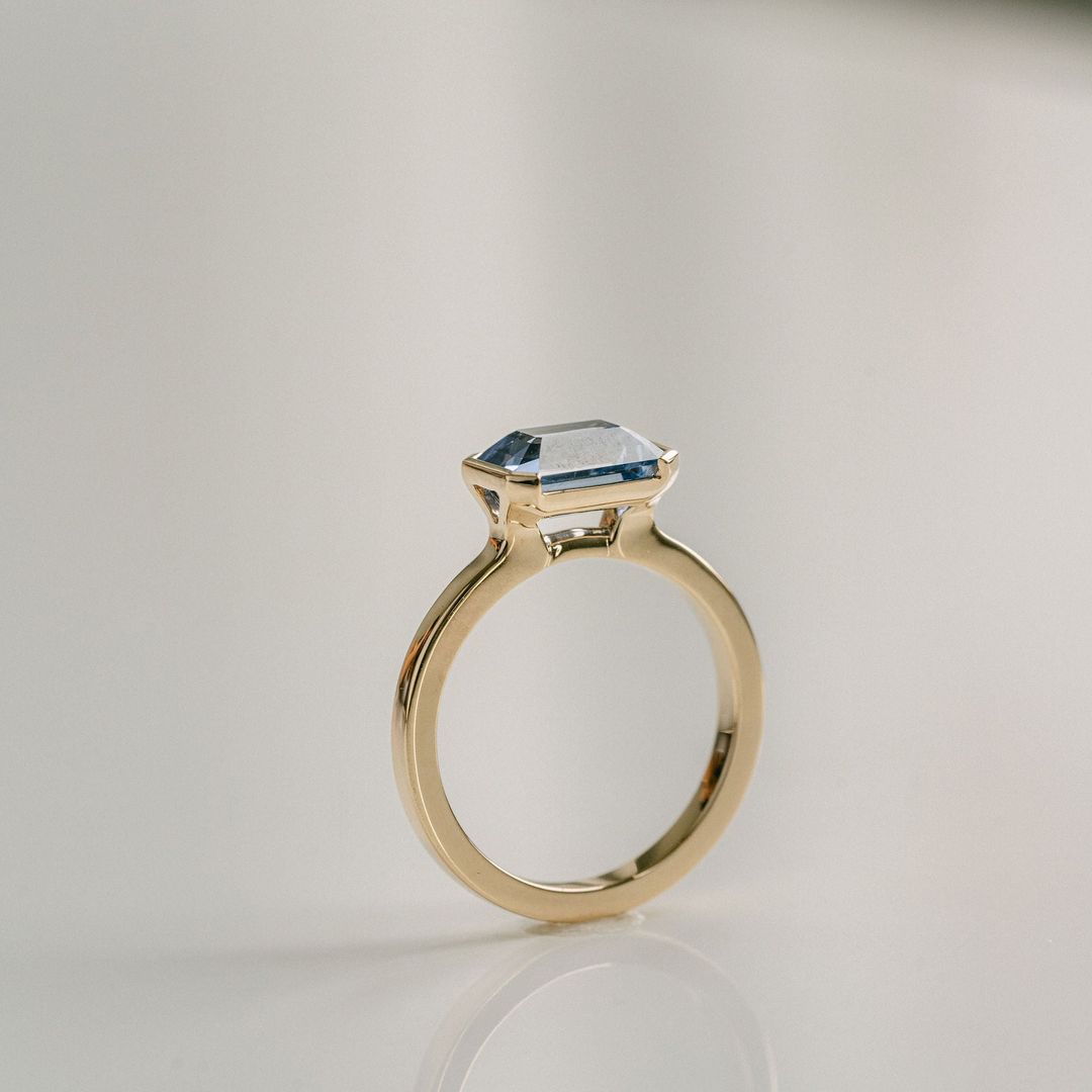 Emerald Cut Blue Sapphire East-West Half Bezel