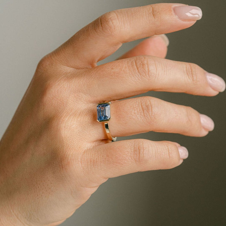 Emerald Cut Blue Sapphire East-West Half Bezel